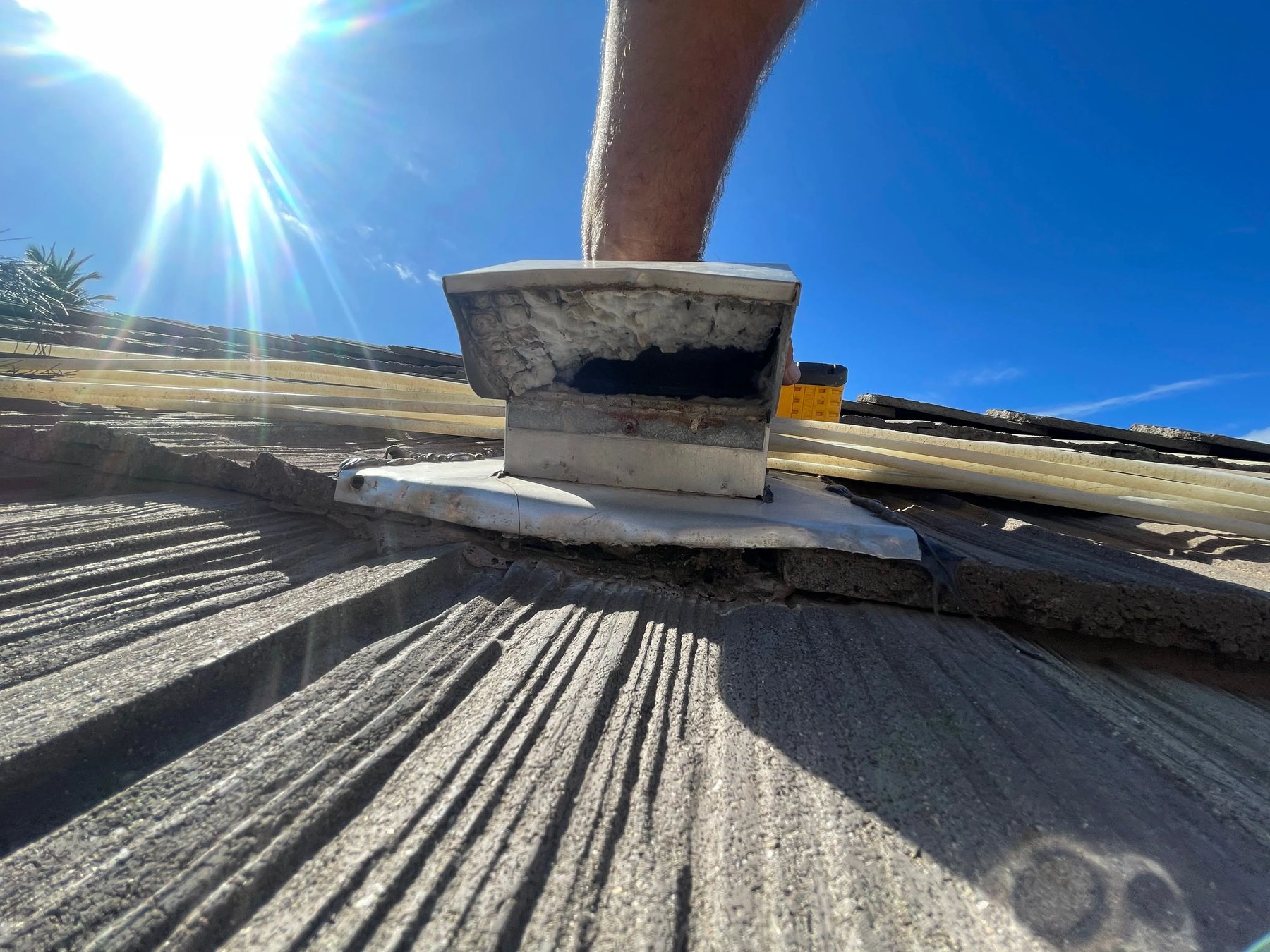 Rooftop vent opening with visible lint and debris around the cover.